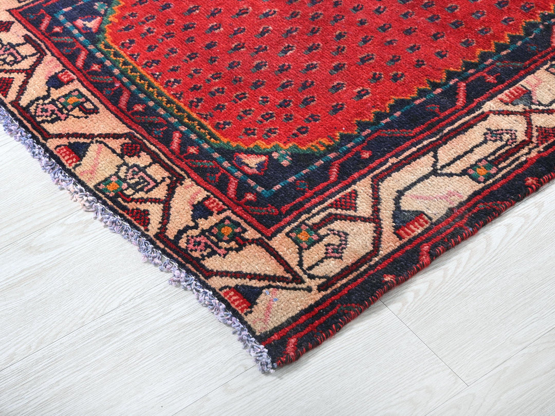 a red rug with a blue border on a white floor
