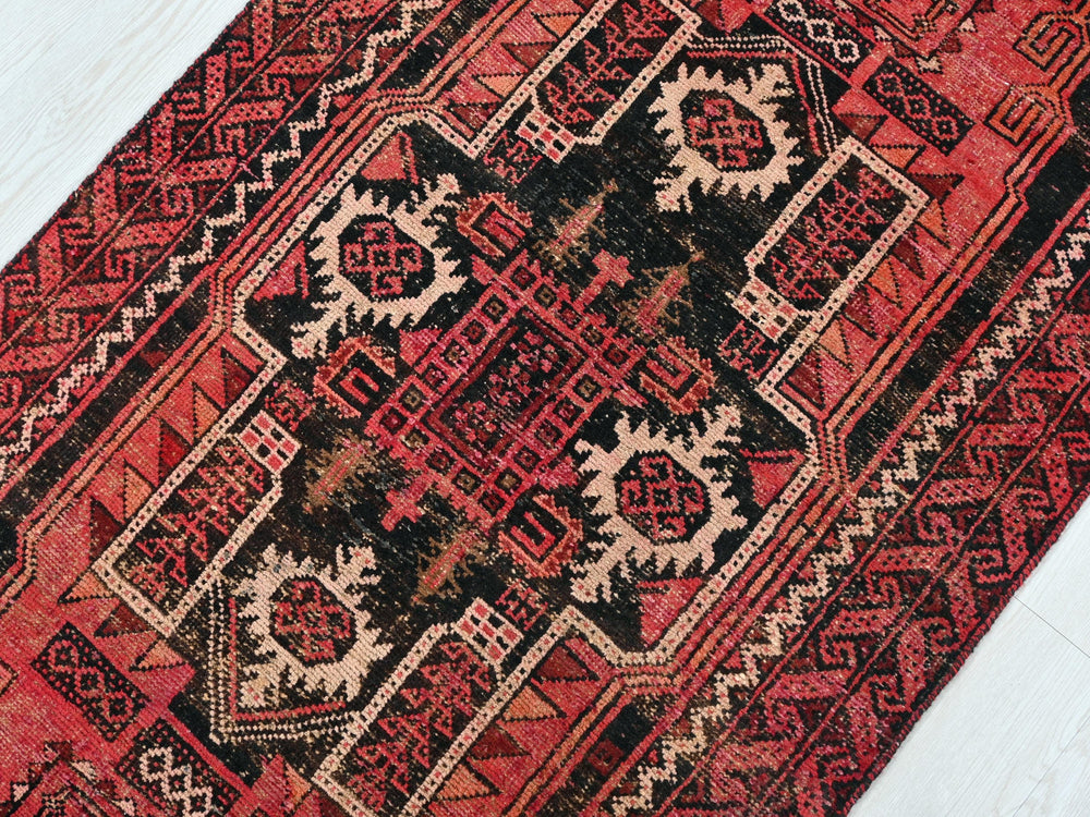 a red and black oriental rug on a white floor