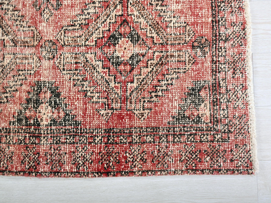 a red and black rug on a white surface