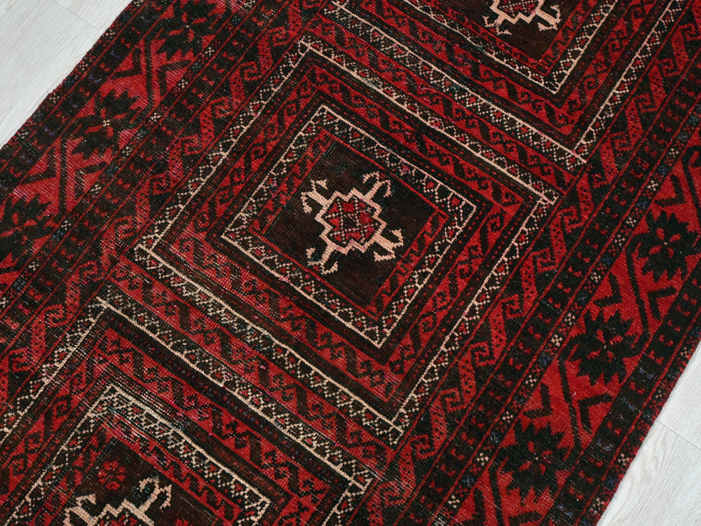 a red and black rug on a white floor