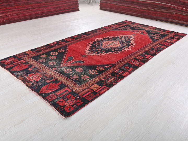a red and black rug on a white floor