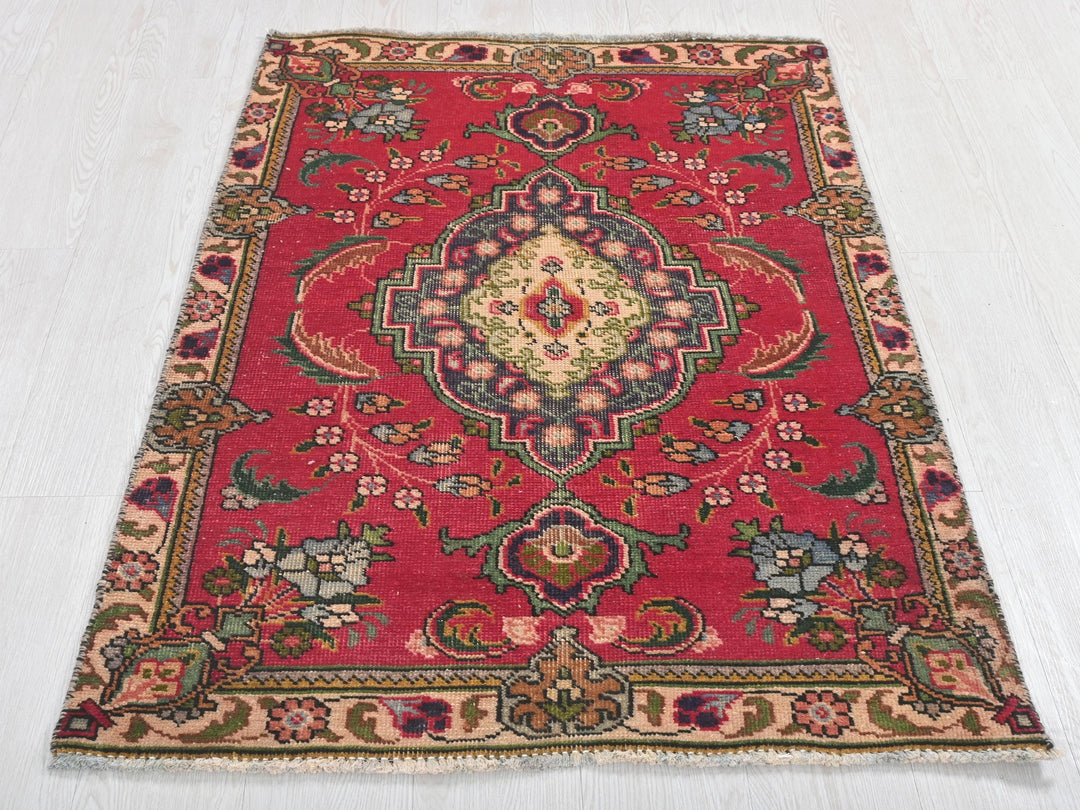 a red rug with a floral design on a white floor