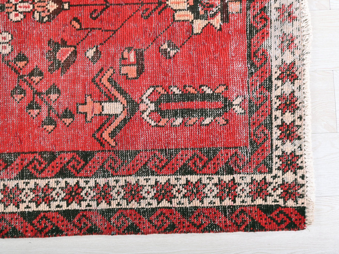 a red oriental rug on a white wooden floor