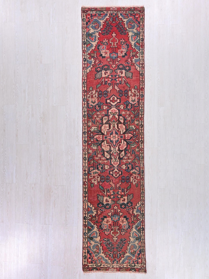 a red rug hanging on a white wall