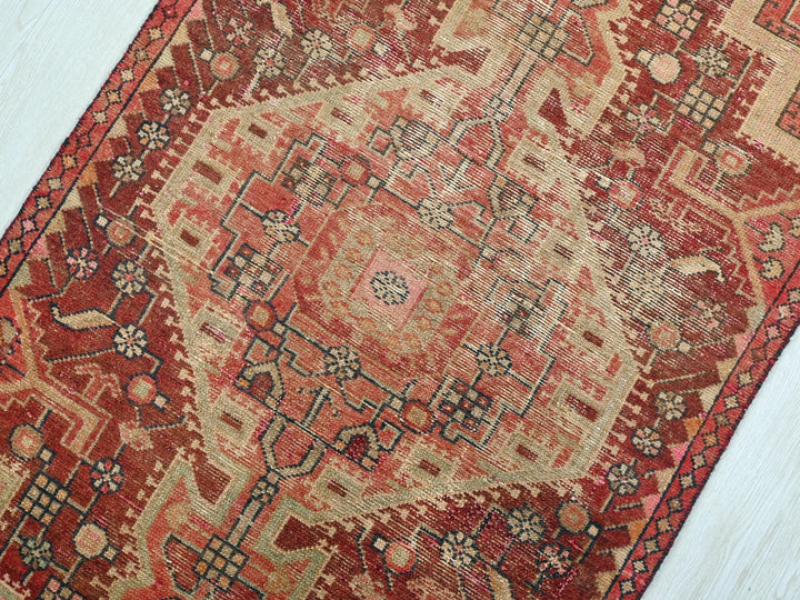 a red and beige rug on a wooden floor