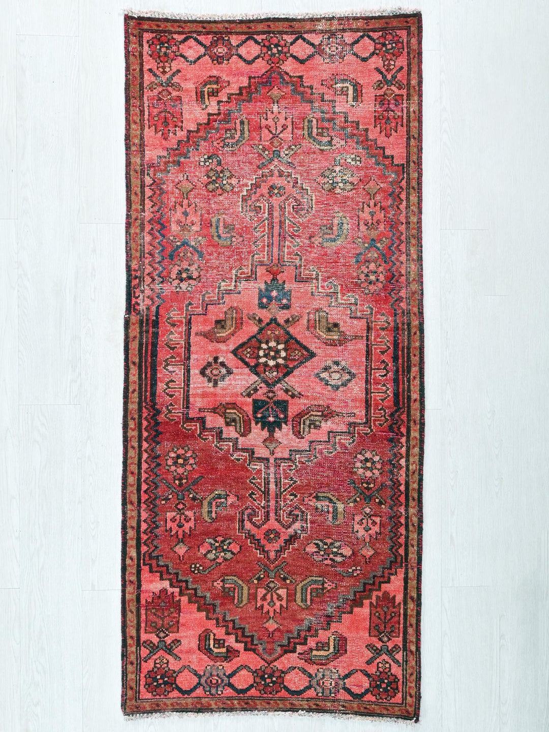 a red rug hanging on a white wall