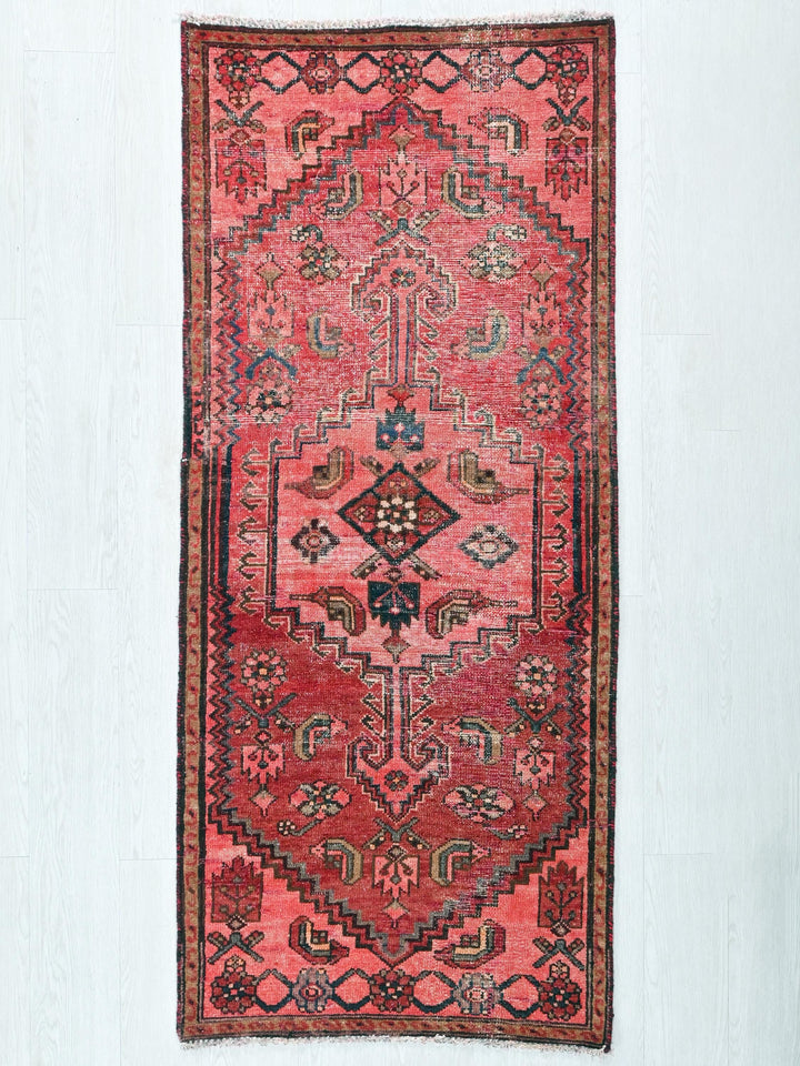 a red rug hanging on a white wall