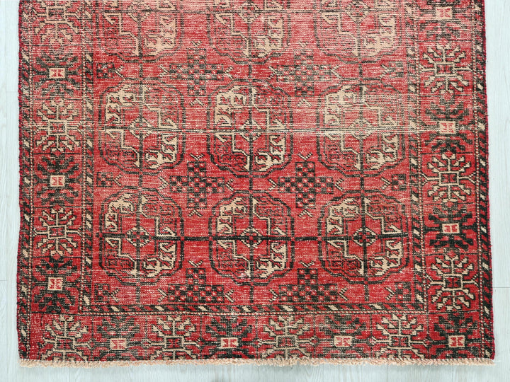 a red and black rug on a wooden floor