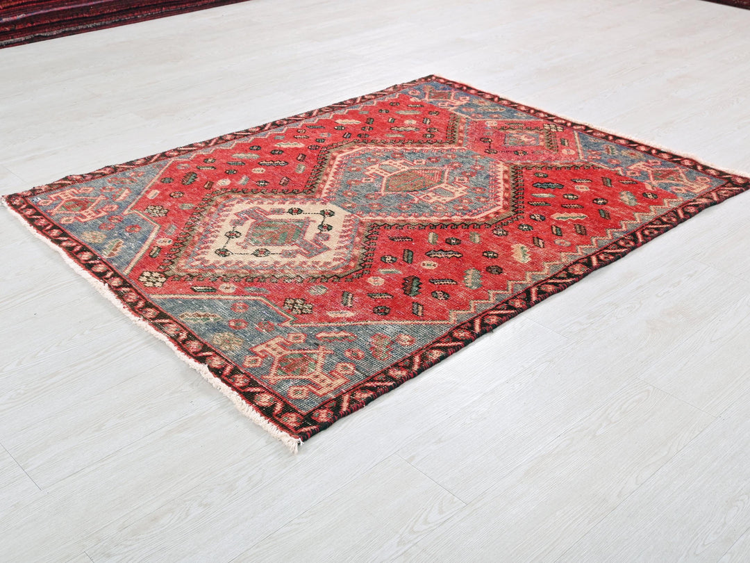 a red and blue rug sitting on top of a white floor