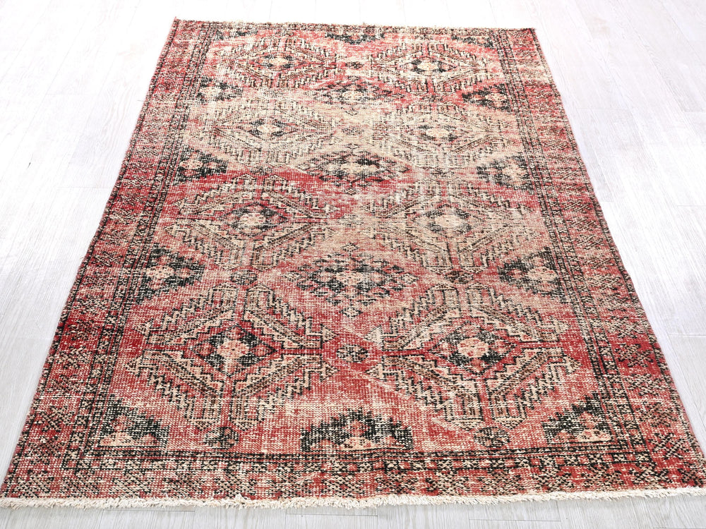 a red and black rug on a white floor