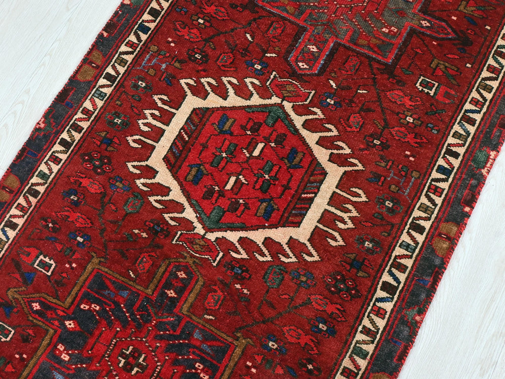 a red rug with a white border on a wooden floor