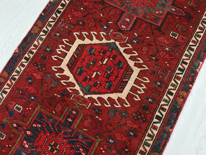 a red rug with a white border on a wooden floor