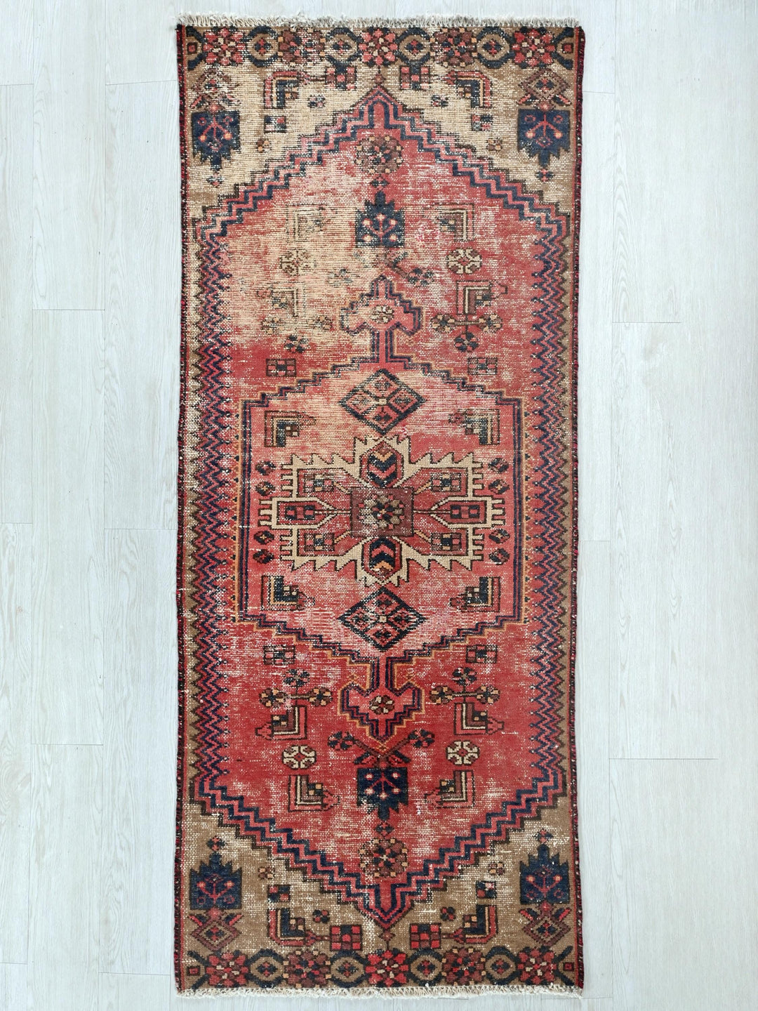 a red rug with a design on the middle of it