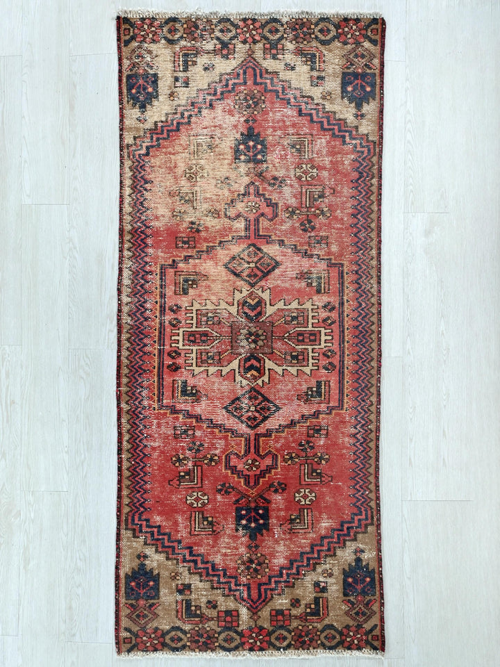a red rug with a design on the middle of it
