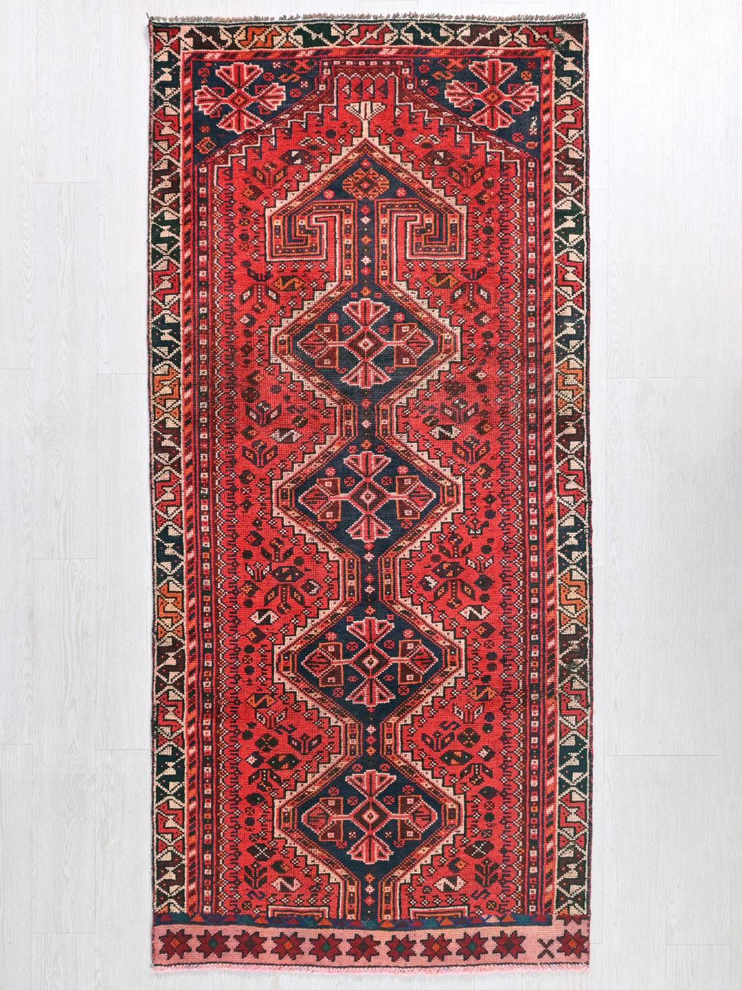a red and black oriental rug hanging on a wall