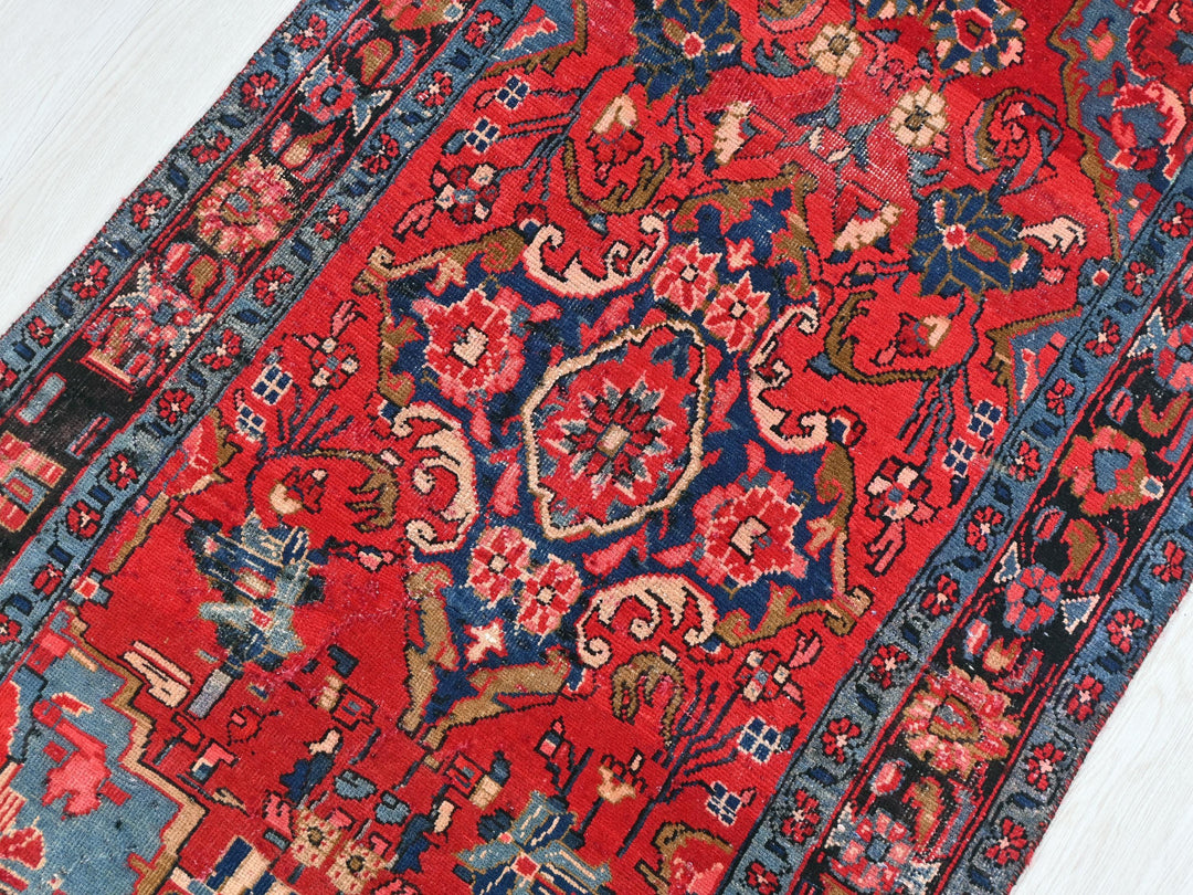 a red rug with a blue border on a white floor
