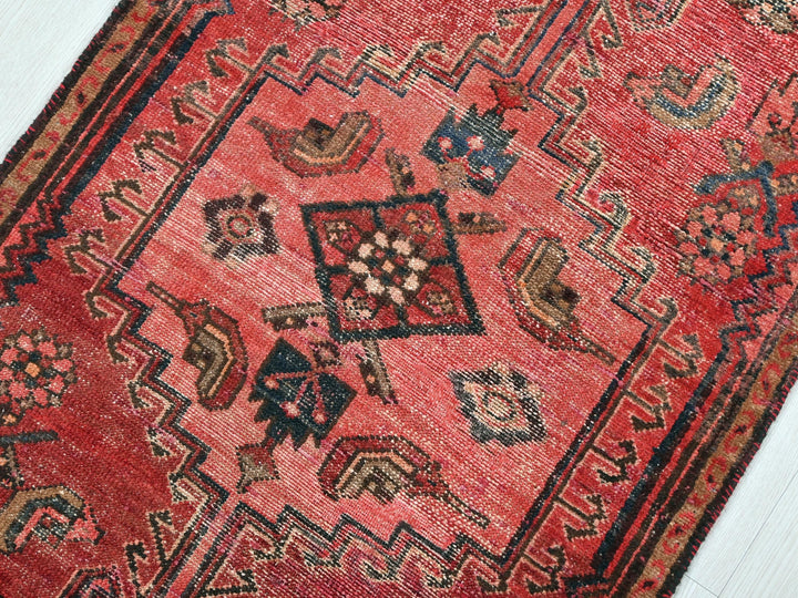 a red rug with a black border on a white floor