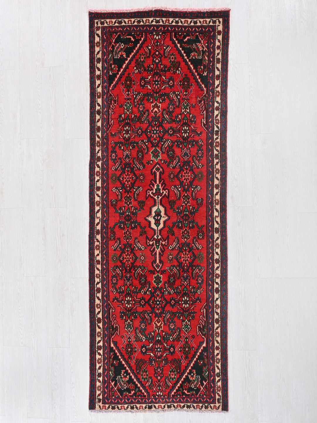 a red rug hanging on a white wall