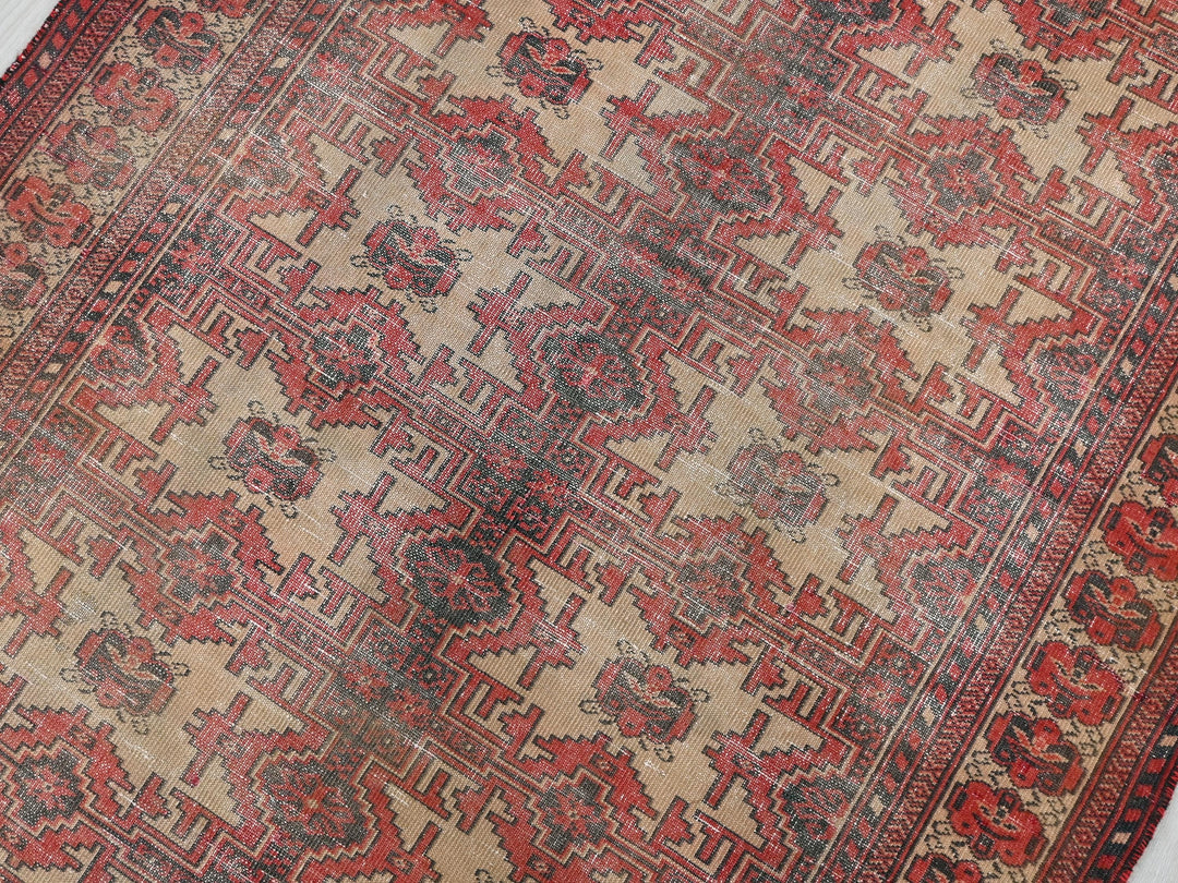 a red and beige oriental rug on a white floor