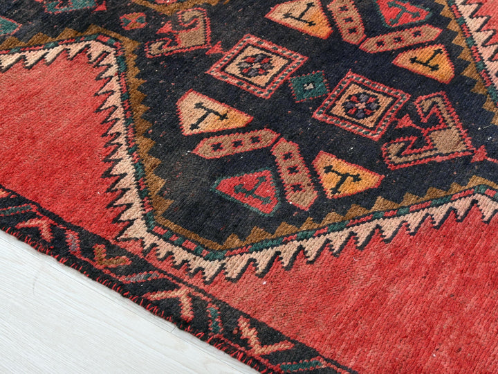 a red and black oriental rug on a white floor