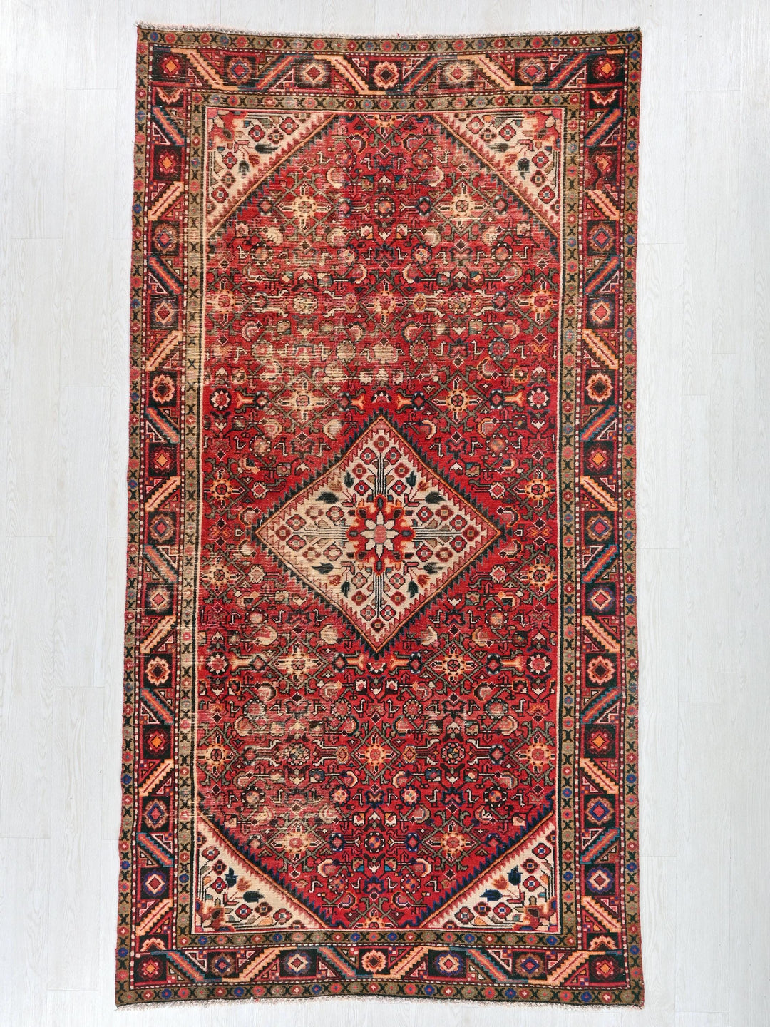 a red rug hanging on a white wall