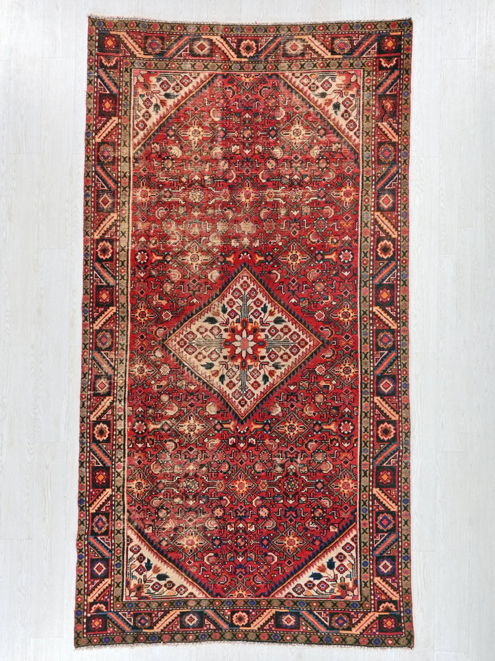 a red rug hanging on a white wall