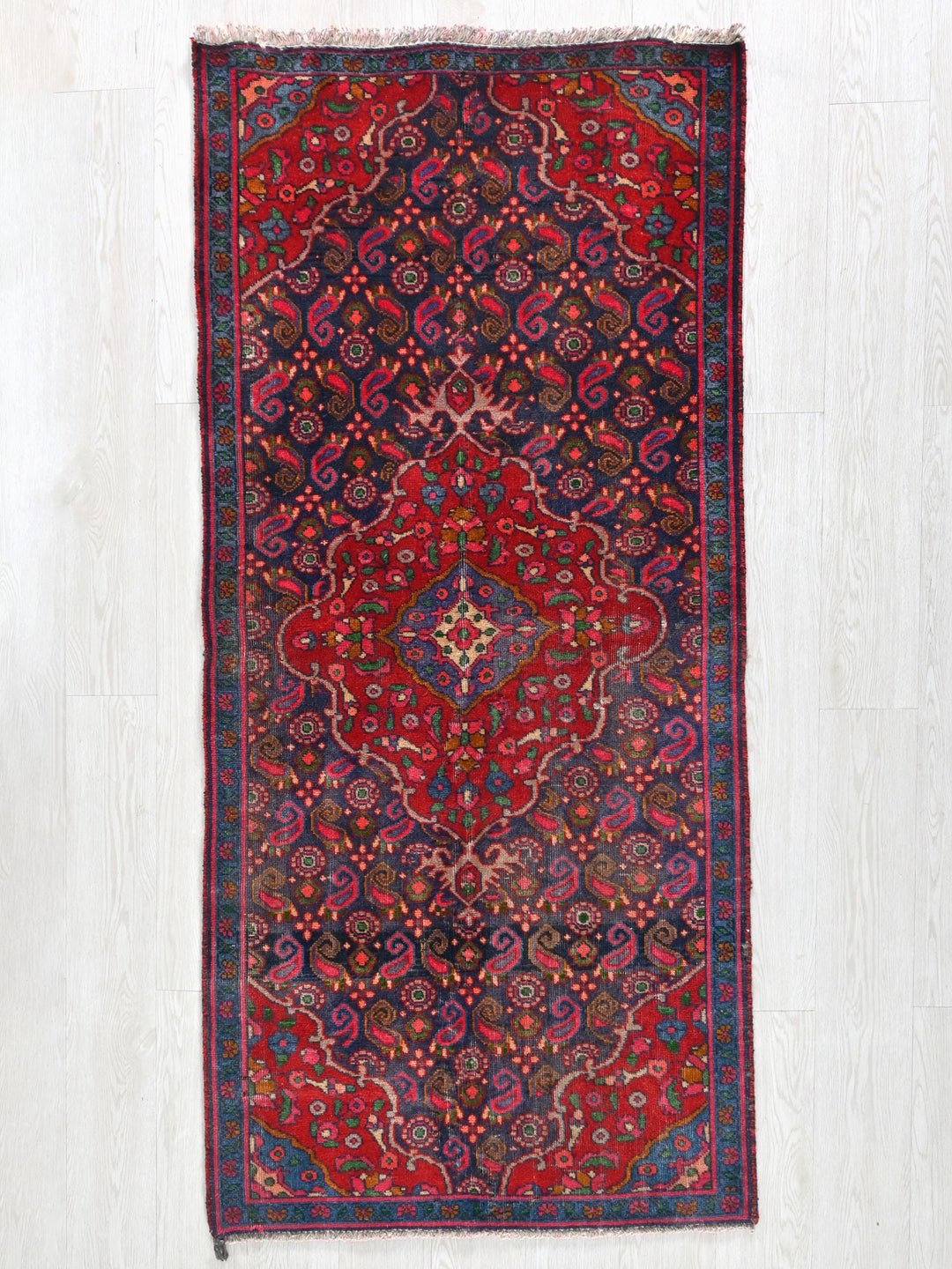 a red and blue rug hanging on a wall