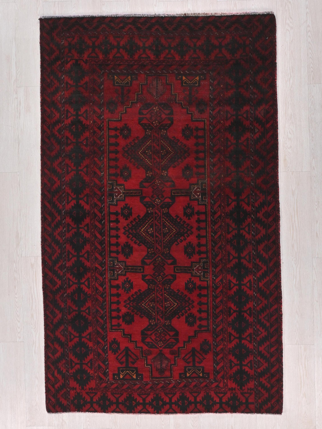 a red and black rug on a white floor