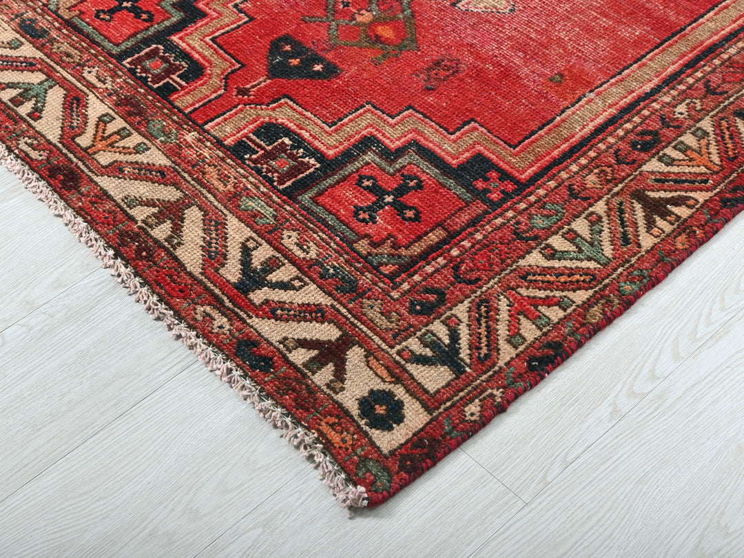 a red oriental rug on a white wooden floor