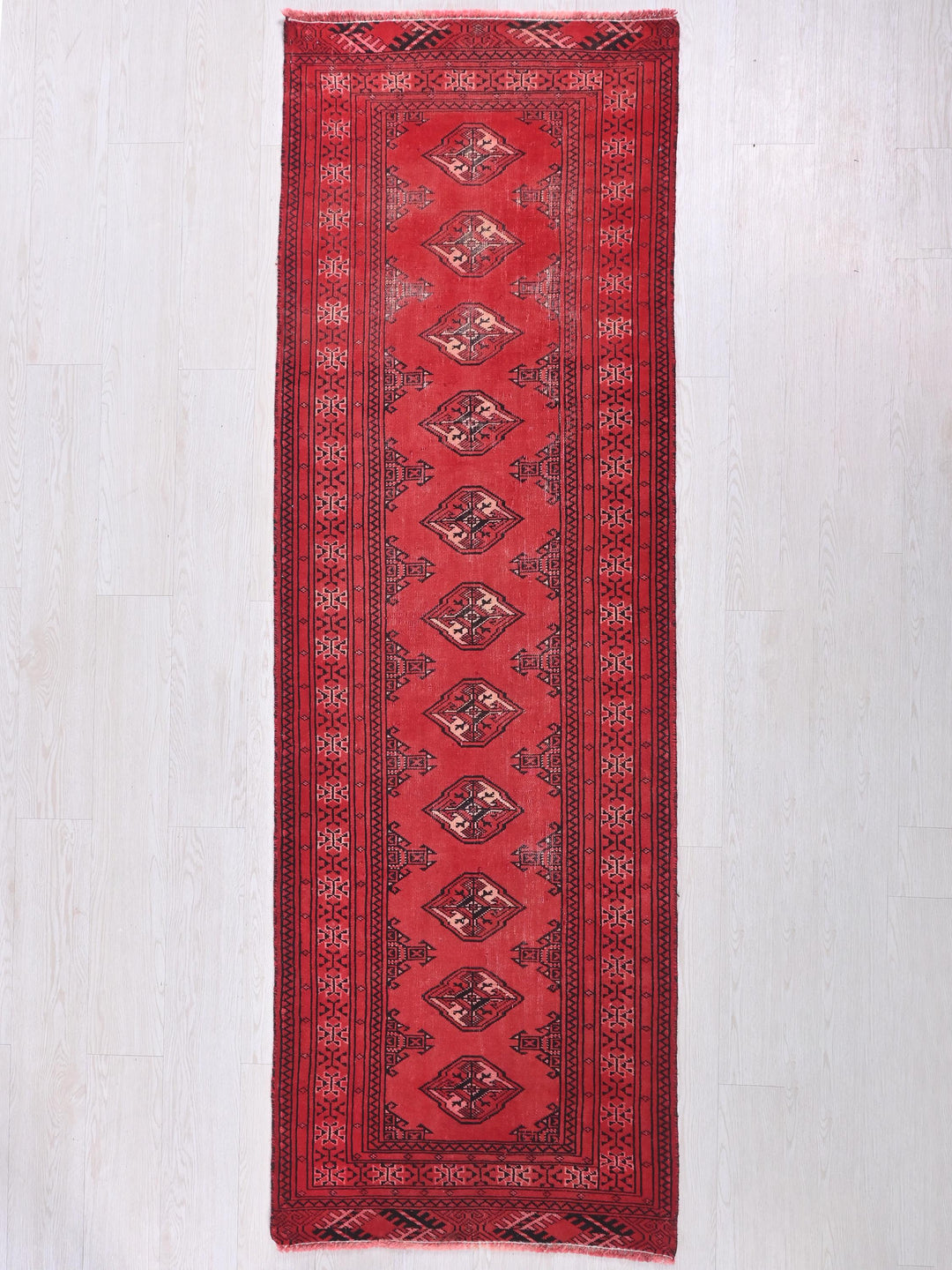 a red rug hanging on a white wall