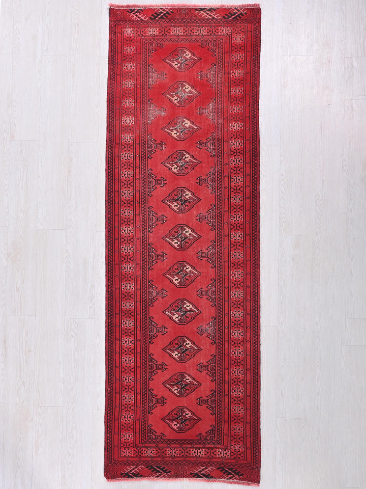 a red rug hanging on a white wall