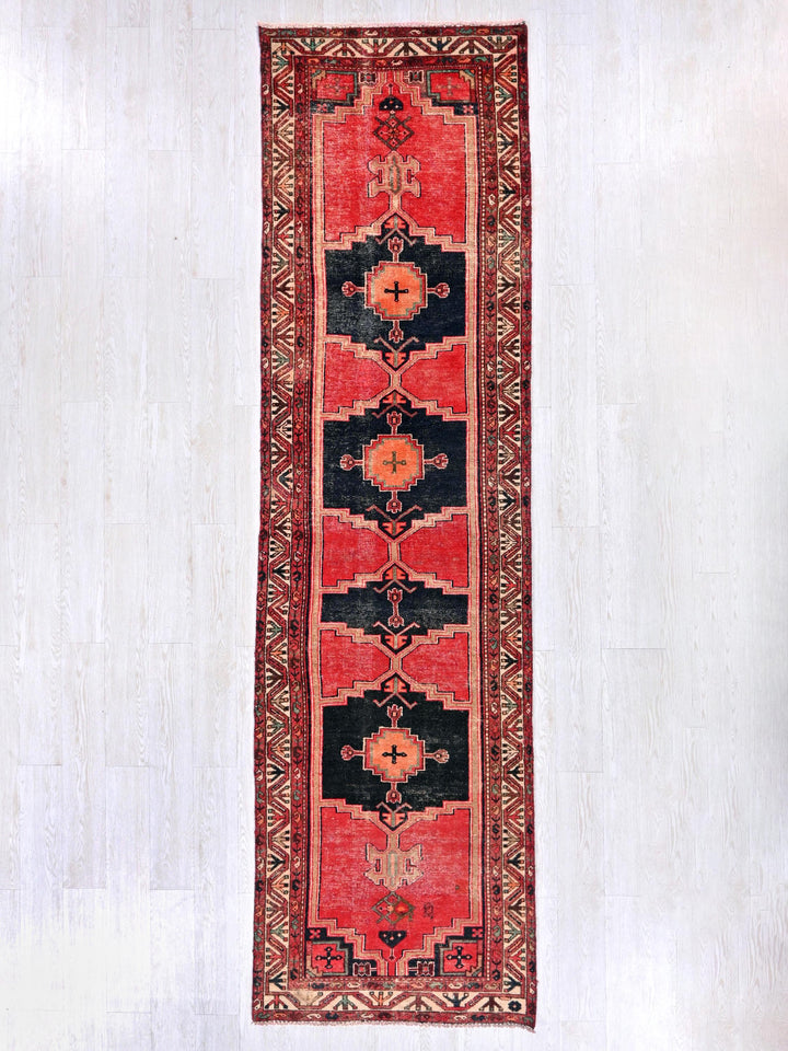 a red and black rug hanging on a wall
