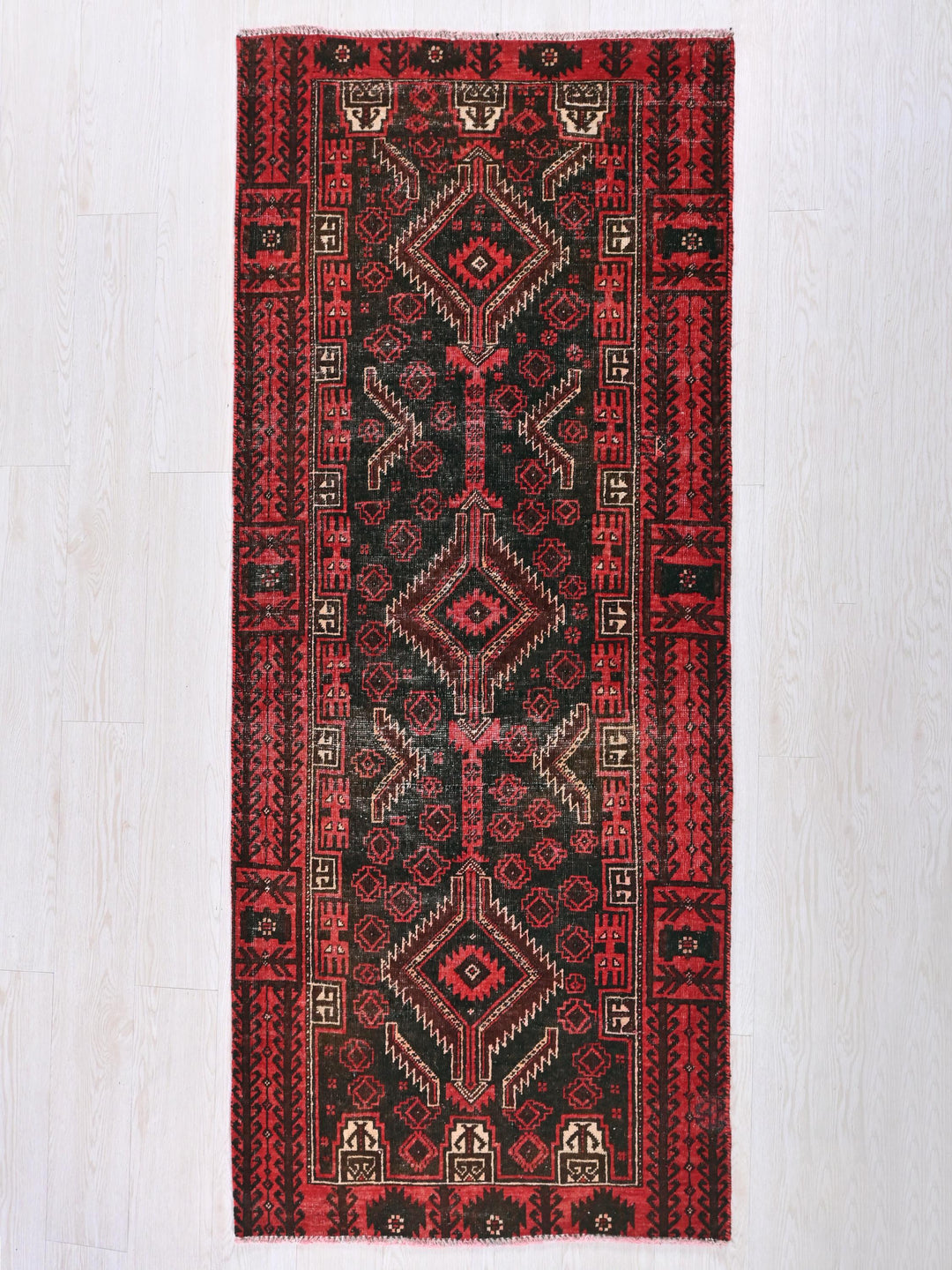 a red and black rug on a white floor