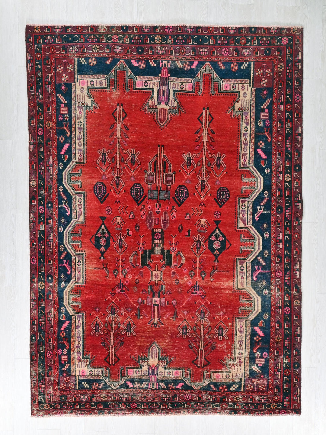 a red rug with a blue border on a white wall