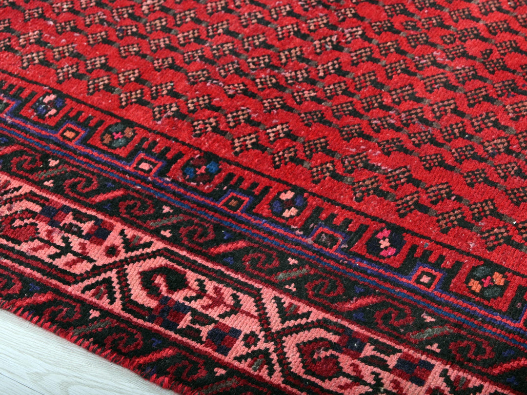 a close up of a red rug on a wooden floor