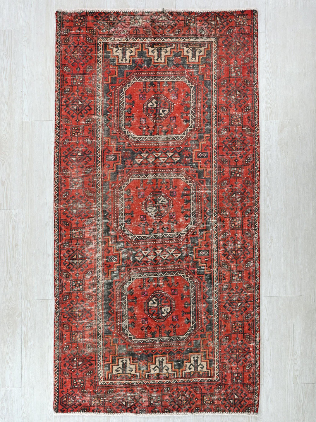 a red rug with a design on the middle of it