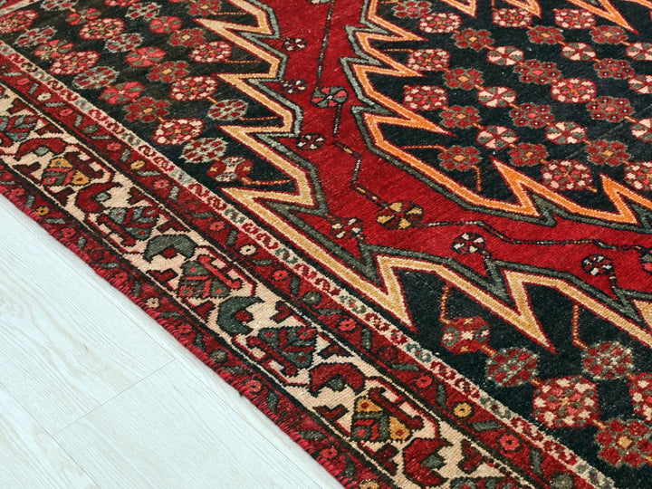 a red oriental rug on a white wooden floor