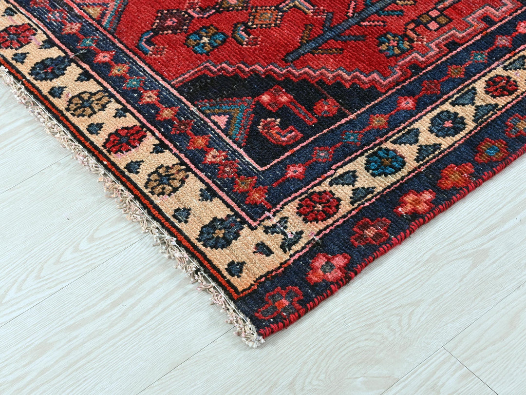 a red and blue oriental rug on a white wooden floor