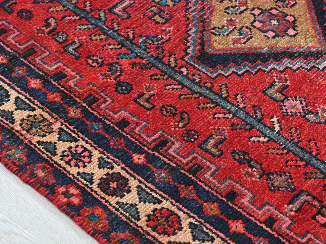 a close up of a red rug on a wooden floor