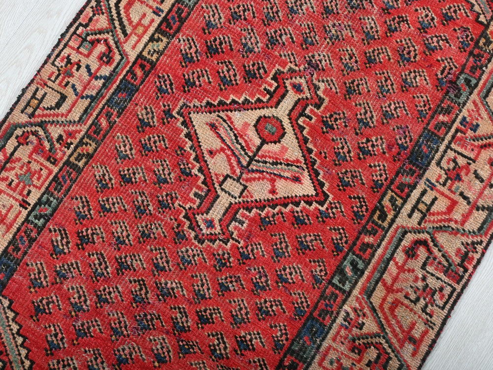 a red oriental rug on a white wooden floor