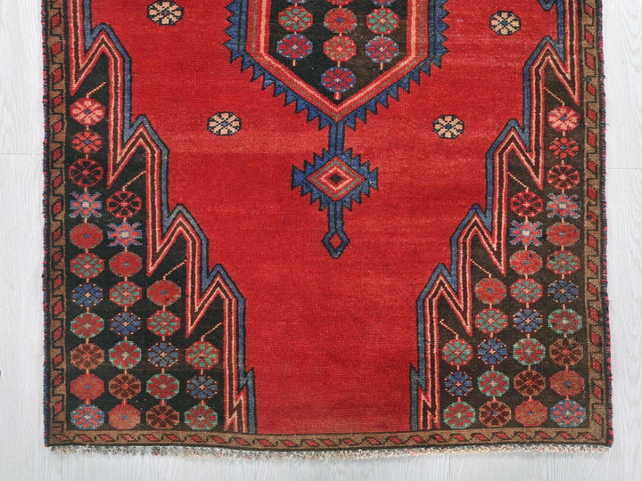 a red rug with a design on the middle of it