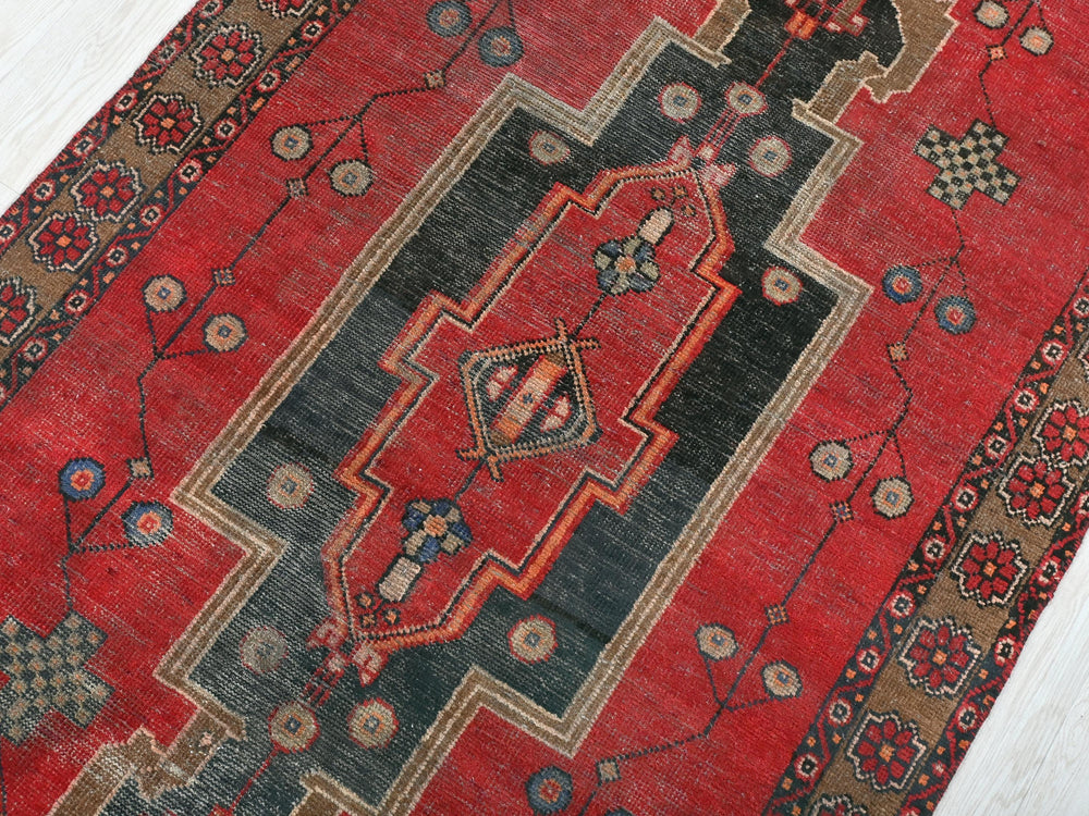 a red rug with a black border on a white floor