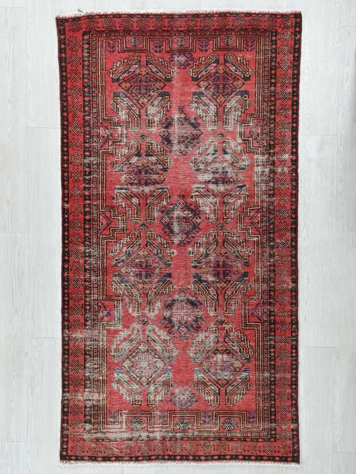 a red rug with a black border on a white floor