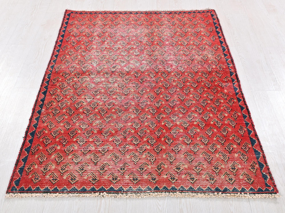 a red rug with a blue border on a white floor