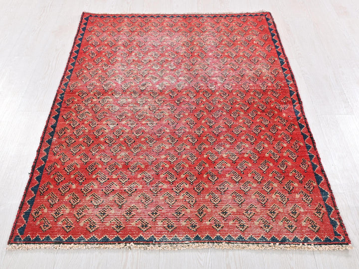 a red rug with a blue border on a white floor