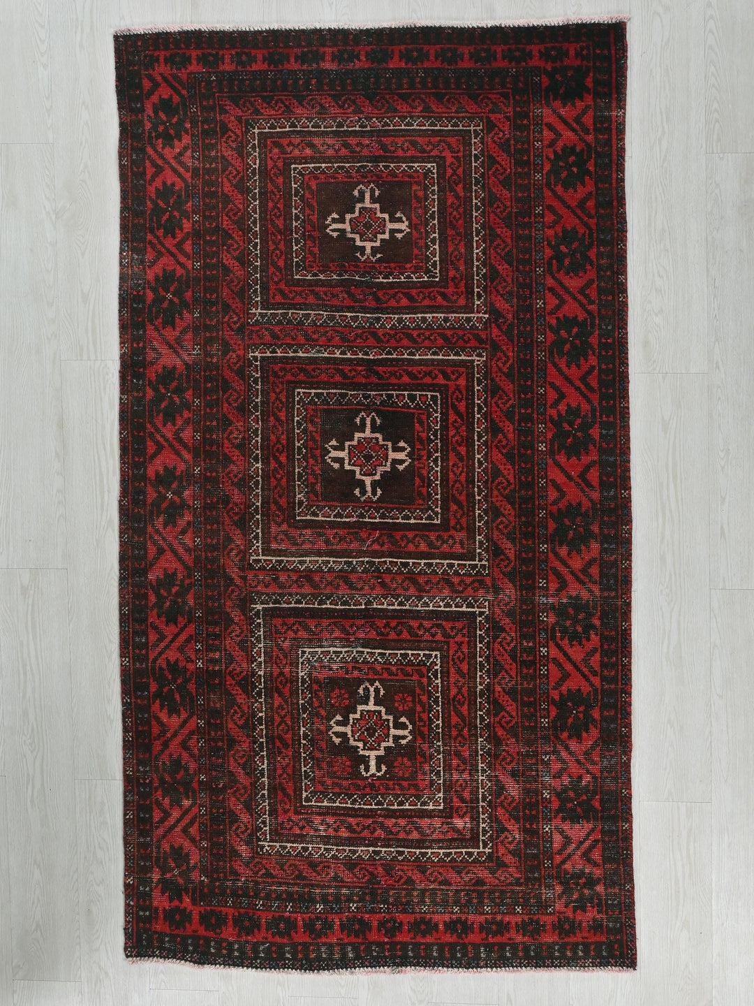 a red and black rug on a white floor