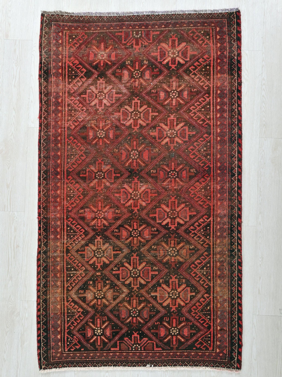 a red and black rug on a white floor