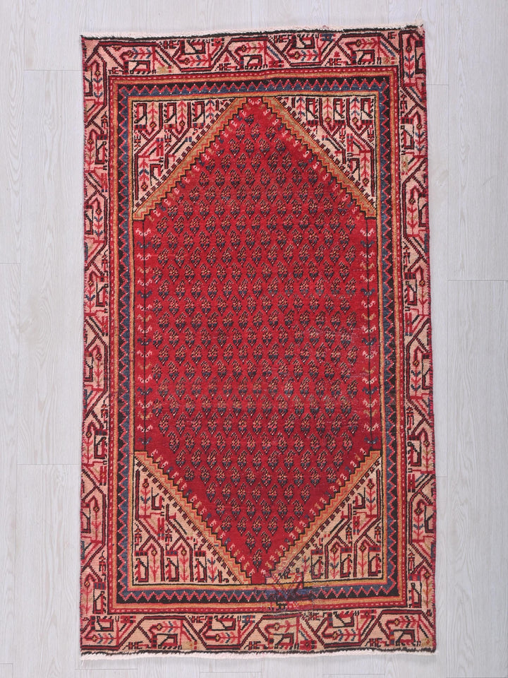 a red rug with a diamond shaped design on it