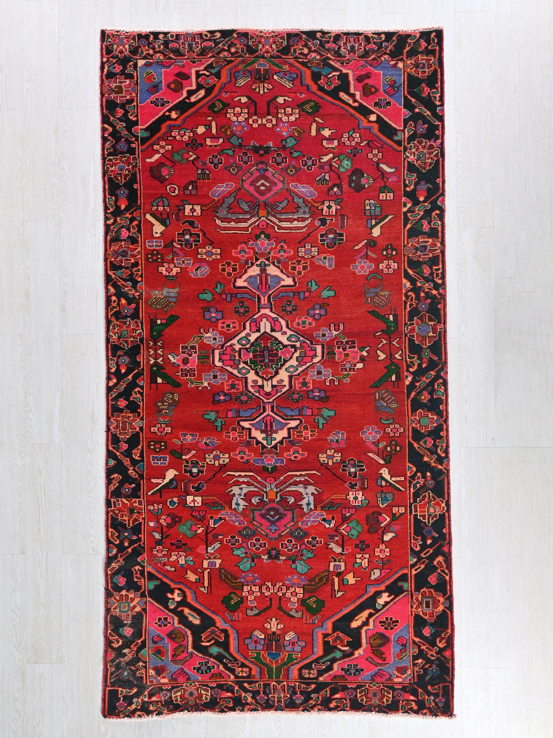 a red rug with a black border on a white floor