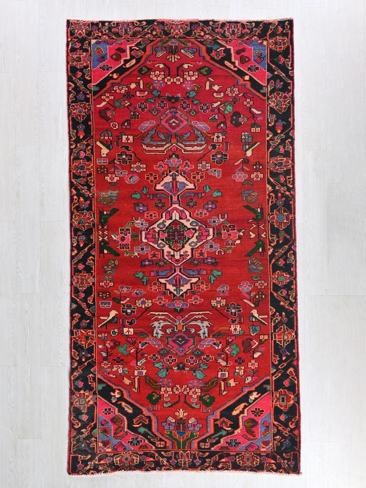a red rug with a black border on a white floor
